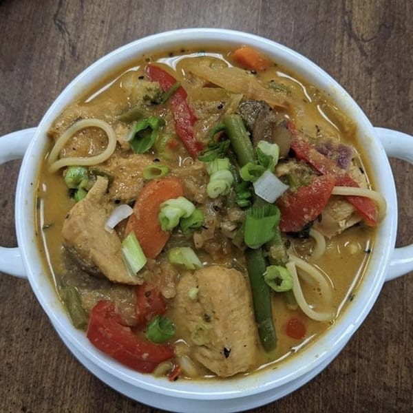Makalu Himalayan Sherpa Restaurant's Indian curry with chicken, noodles, and vegetables in a white bowl.